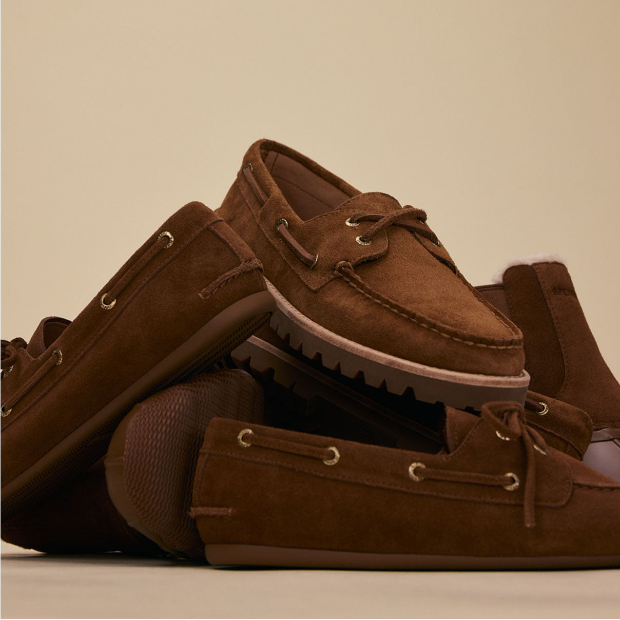 Several brown suede loafers and boat shoes in a pile